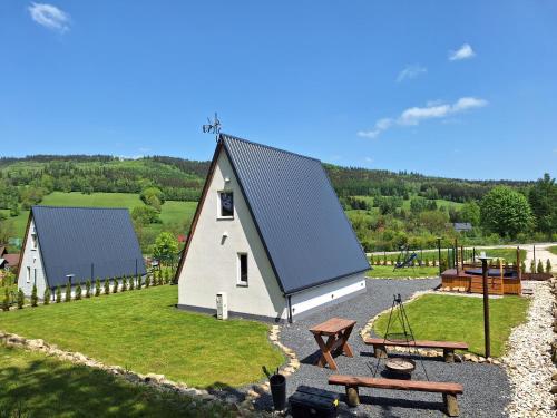 a small white barn with a picnic table and benches at Domki na Sudeckiej Polanie in Stronie Śląskie