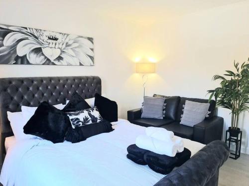 a bed with black and white pillows and a couch at Green Apartments in Invergowrie