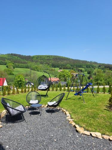 a group of chairs and swings on a playground at Domki na Sudeckiej Polanie in Stronie Śląskie