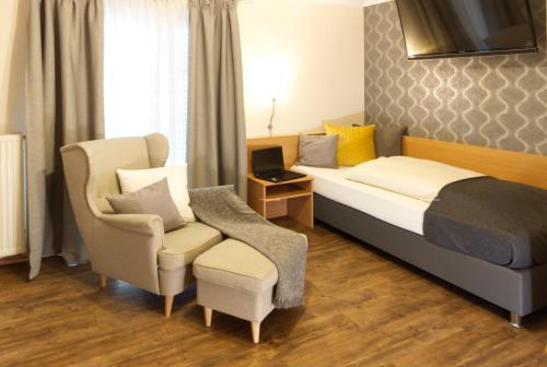 a hotel room with a bed and a chair at Gästehaus Zehmerhof bei Erding in Walpertskirchen
