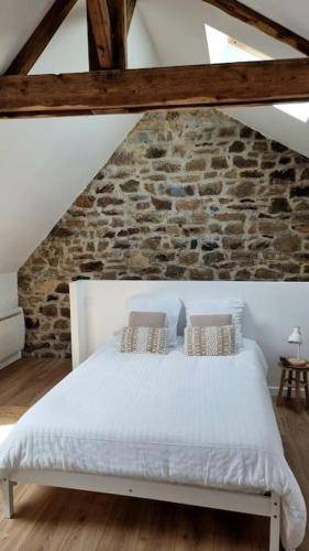 - une chambre avec un lit blanc et un mur en pierre dans l'établissement Le P'tit Indus , Duplex, à Lanester