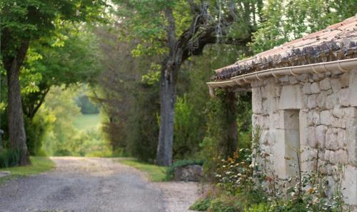 a stone building next to a road with trees at Mas Labrugade in Lebreil
