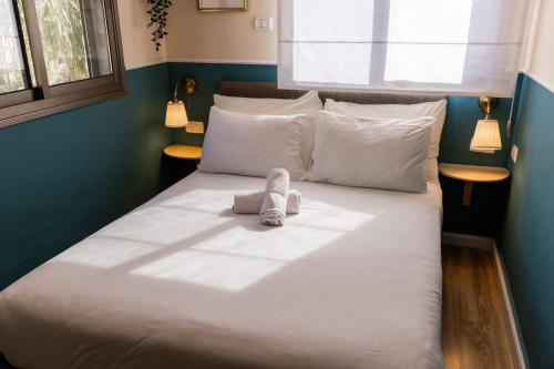 a large white bed with a stuffed animal on it at Domus Bat Galim Hotel in Haifa