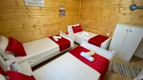 3 Betten in einem rot-weißen Zimmer in der Unterkunft Bujtina Miqesia in Theth