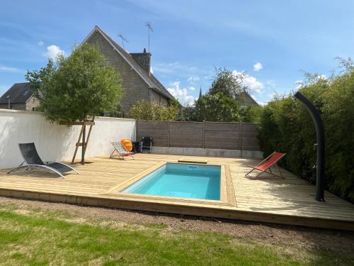 a small swimming pool on a wooden deck with two chairs at Charmante maison avec piscine in Beaussais sur Mer