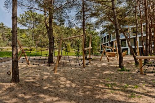 a swing set in a park with trees at Apartamenty Wydma & Las BlueApart in Jastarnia