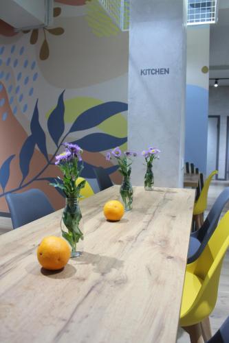 a wooden table with vases of flowers and oranges on it at izzzi hostel in Bishkek