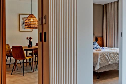 a bedroom with a bed and a dining room with a table at Apartamenty Wydma & Las BlueApart in Jastarnia
