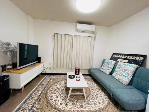 un soggiorno con un divano blu e una TV di 竹苑（一戸建て）露天温泉歩い1分間・梅田まで12分・天神橋六町目歩いて7分間 ad Osaka