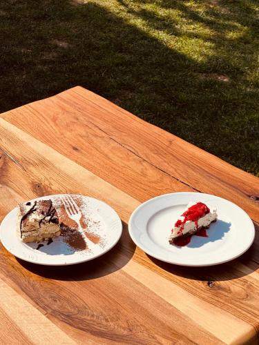 two pieces of cake on plates on a wooden table at Bianca Hotel & Villa in Tirana
