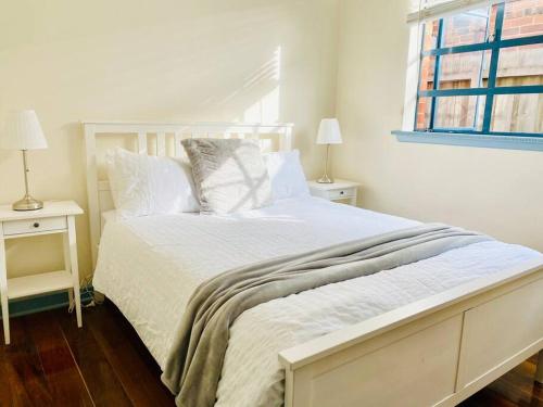 a white bed in a bedroom with two night stands at Bay Rd Kids & Pet Friendly Free Parking in Cheltenham