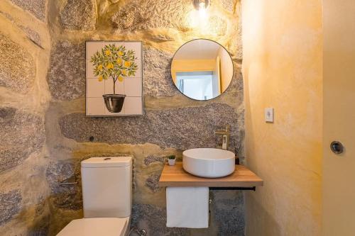 Un baño con lavabo, inodoro y espejo. en Lemon House, en Valpedre
