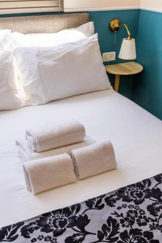 a bed with two folded towels on it at Domus Bat Galim Hotel in Haifa