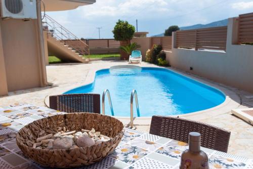 una mesa con una cesta de rocas junto a una piscina en Glamour beautique villa, en Acarnas