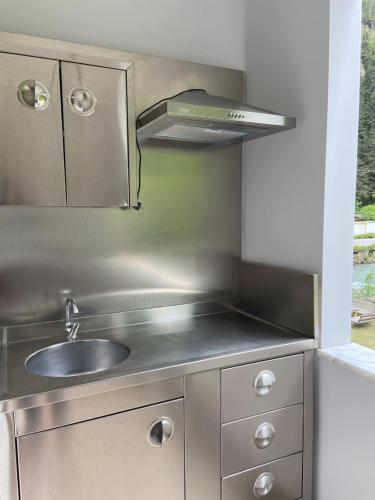 a stainless steel kitchen with a sink and a hood at Uzungol Soylu Hotel in Uzungöl
