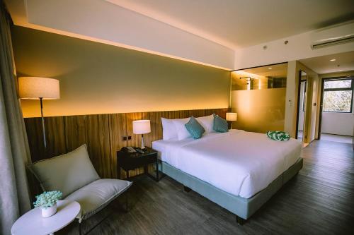 a bedroom with a large bed and a chair at The Maximilian Hotel in Cauayan City