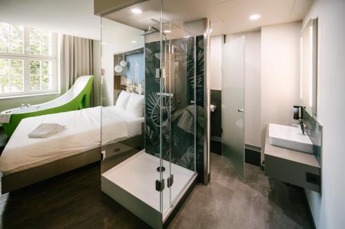 a bathroom with a shower and a bed and a sink at Travel24 Hotel Leipzig City in Leipzig