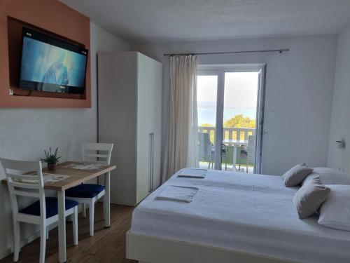 a bedroom with a bed and a table and a television at Guesthouse Dominović in Brela