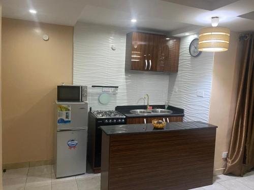 uma pequena cozinha com um frigorífico e um fogão em Studio B, (Studio Apartment) Hillside Gardens em Lagos