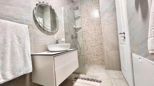 een witte badkamer met een wastafel en een spiegel bij Zeus Tirana Suite in Tirana