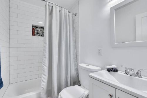 La salle de bains blanche est pourvue de toilettes et d'un lavabo. dans l'établissement Pet Friendly Pool Home in Hollywood 8 min to Beach, à Hollywood