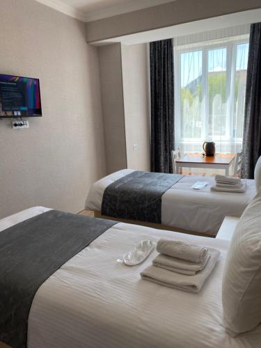 two beds in a hotel room with towels on them at Hotel Sharl in Ninotsminda