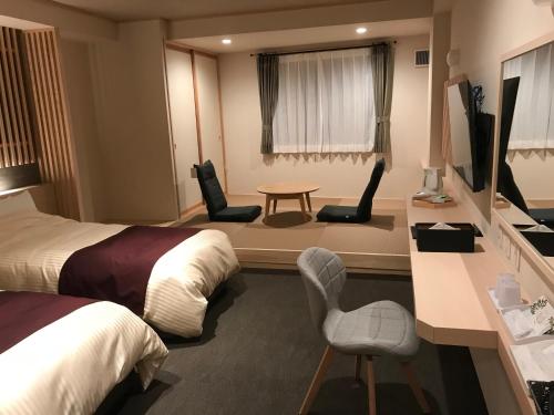 會津若松的住宿－Aizu Tsuruya Hotel，酒店客房带两张床和一张桌子以及椅子。