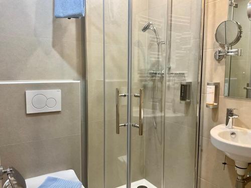 a shower with a glass door next to a sink at Hotel Royal in Villingen-Schwenningen