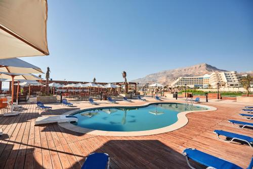 a swimming pool with chairs and a mountain in the background at Tolip Resort El Galala Majestic in Ain Sokhna