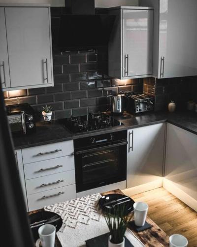 a kitchen with white cabinets and a black stove top oven at Comfortable Home In Bolton in Farnworth