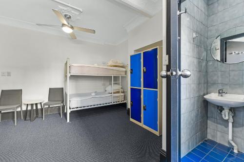 a room with a bathroom with a sink and a mirror at London Plane Backpackers in Sydney