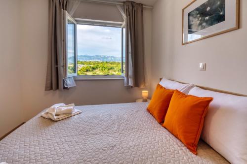 a bedroom with a bed with orange pillows and a window at Rock Apartments II in Novalja