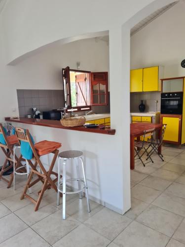 a kitchen with chairs and a counter with yellow cabinets at Villa Odette in Beauséjour