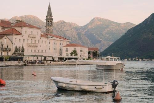 a small boat in the water in front of a building at M&M apartment & rooms in Perast