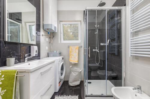a bathroom with a shower and a sink and a washing machine at Apartman Darija in Vodnjan