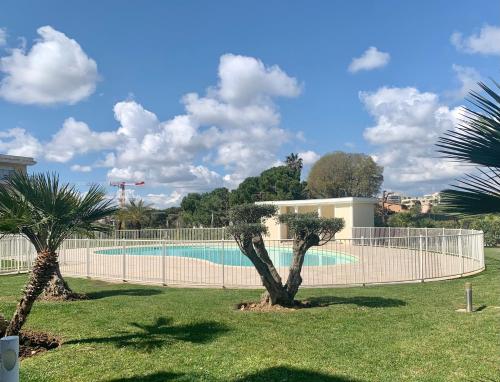 - une piscine avec deux palmiers dans une cour dans l'établissement Joli studio climatisé avec Jardin dans résidence avec piscine, à Antibes
