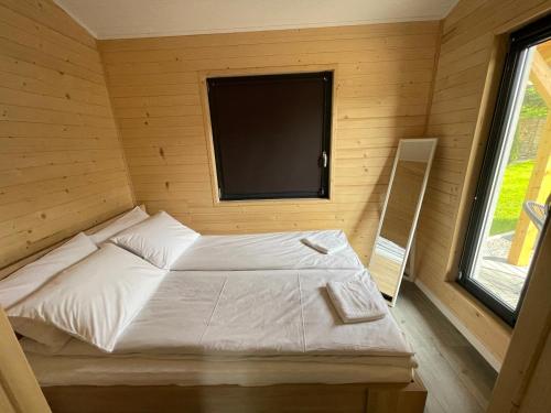 a small bedroom with a bed and a television at RedDoor Zator Lake Houses in Zator