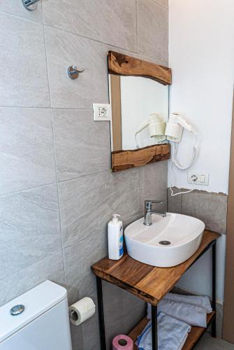 a bathroom with a sink and a mirror and a toilet at N'konak Guesthouse in Pukë