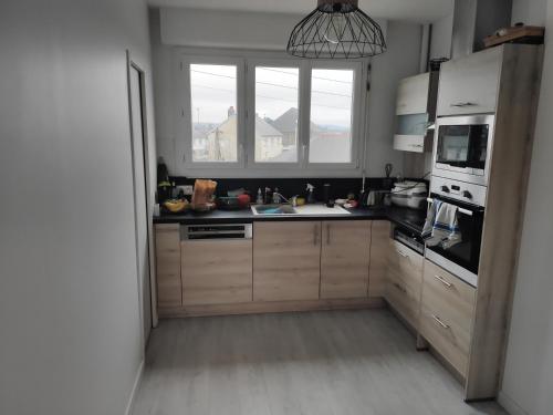 une cuisine avec des armoires en bois, un évier et une fenêtre dans l'établissement Fougères 77 m2, 2 chambres, garage , Balcon, à Fougères