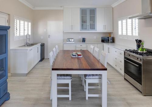 uma cozinha com uma mesa de madeira e armários brancos em Seafront Retreat in Sandbaai em Hermanus