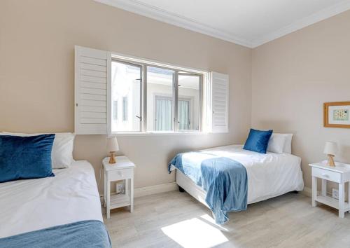 1 dormitorio con 2 camas y ventana en Seafront Retreat in Sandbaai en Hermanus