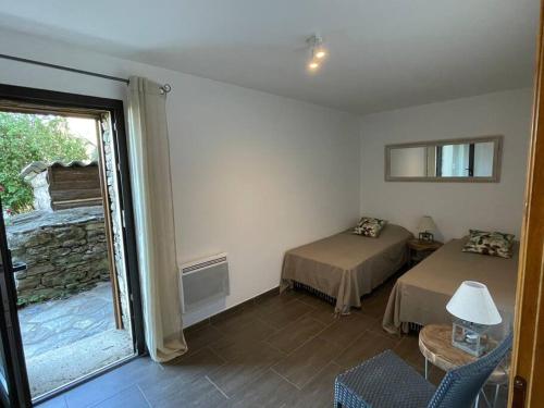 a room with two beds and a sliding glass door at CAP CORSE - SISCO - MAISON DE CHARME 6 PERSONNES in Sisco