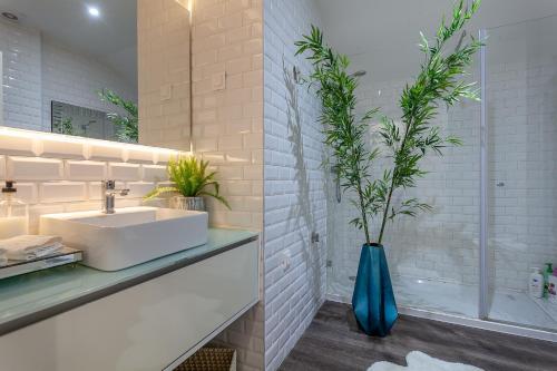 baño con lavabo blanco y jarrón azul con plantas en Urbana Homes by Home Sweet Home Aveiro, en Aveiro