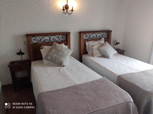 two beds in a hotel room with white sheets at Zé Inácio - Alojamento e Restaurante in Porto Covo