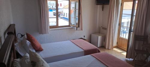 um quarto de hotel com duas camas e uma janela em Zé Inácio - Alojamento e Restaurante em Porto Covo