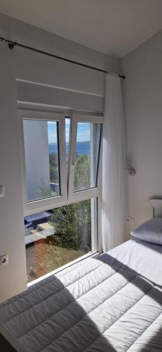 a bedroom with a bed and a large window at Ni-Ka in Pag
