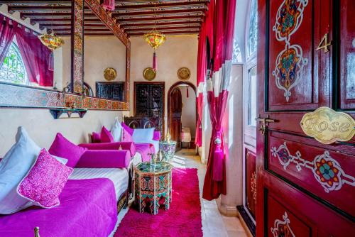 een woonkamer met paarse meubels en roze gordijnen bij Riad Anabel in Marrakesh