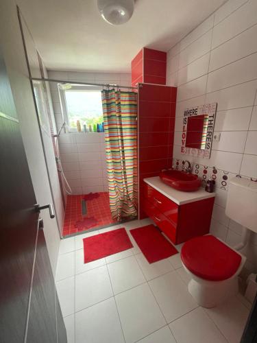czerwona łazienka z czerwoną toaletą i prysznicem w obiekcie Villa Nature w Sarajewie