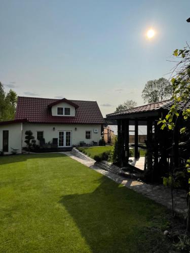 a white house with a green lawn in front of it at Mėta House in Merkinė