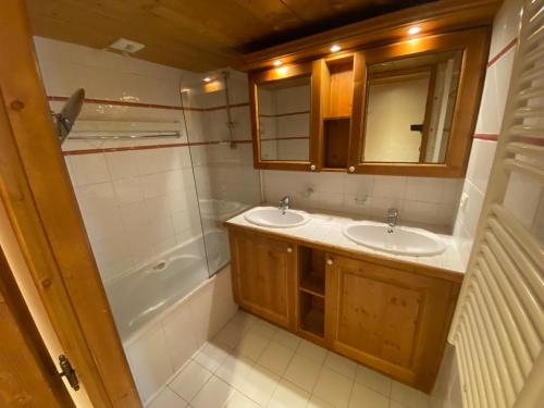 une salle de bain avec deux lavabos, une baignoire et un miroir dans l'établissement Tignes-8-10 personnes-4 chambres-parking, à Tignes
